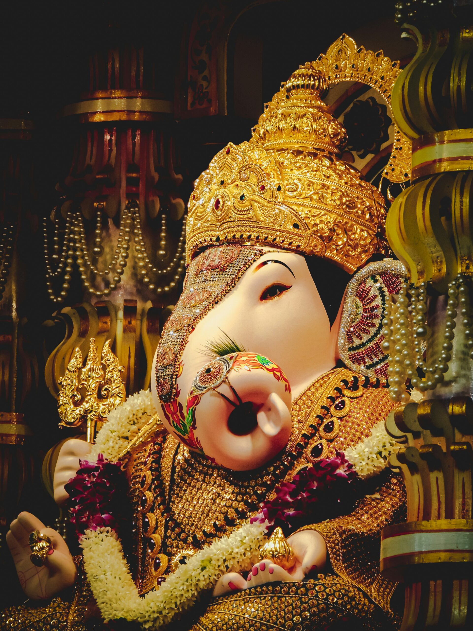 Large Ganesh Chaturthi idol decorated with flowers and lights in a public pandal